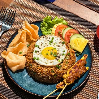 Nasi goreng at Amber Poolside, a fried egg on top with satay and prawn crackers alongside.