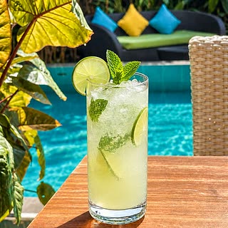 A tall glass of fresh lime juice on a table beside the pool at Amber Poolside.