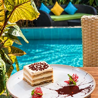 A slice of tiramisu at Amber Poolside with a pink flower on the plate.
