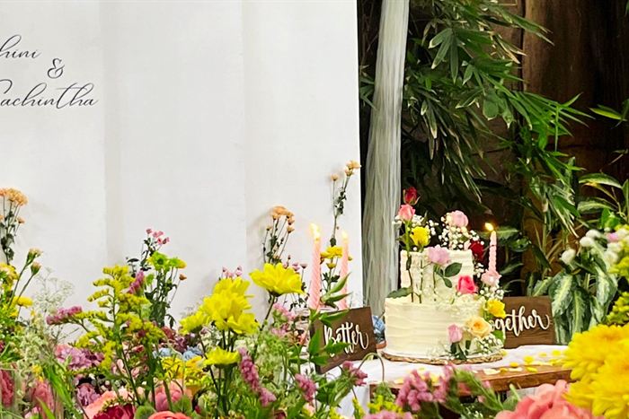 A celebration set up at Amber Poolside, yellow and pink flowers, a small cake and a Better Together sign beside the greenery.