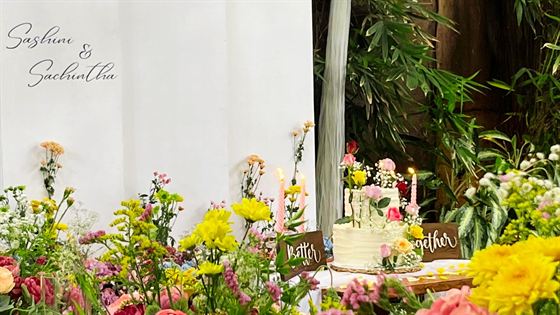 A celebration set up at Amber Poolside, yellow and pink flowers, a small cake and a Better Together sign beside the greenery.