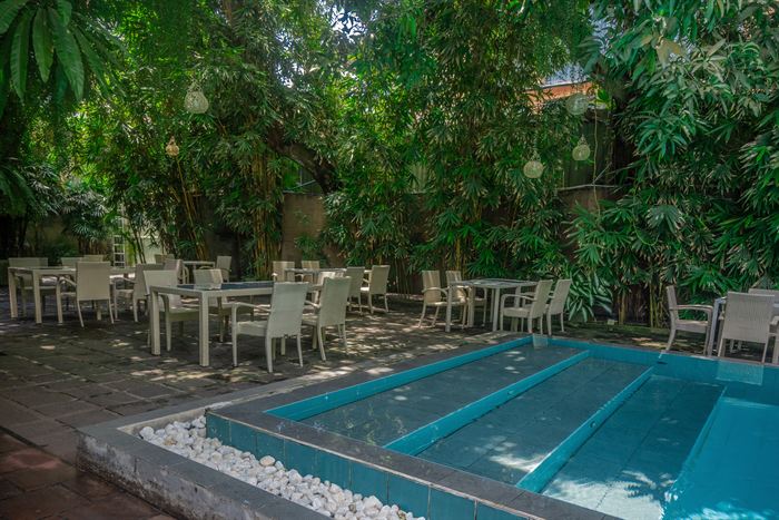 The garden at Colombo Court, tables under dense planting beside the pool.