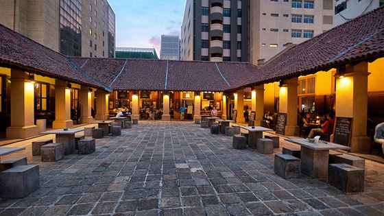 The stone courtyard of the Old Dutch Hospital in Colombo Fort at dusk, lamps lit under the colonnade.