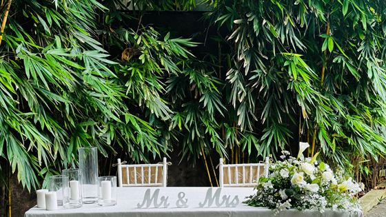 A table laid with white linen and flowers for a wedding beside the pool at Colombo Court.