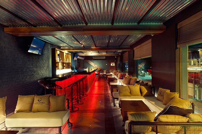 The Loft at Colombo Court, a long bar lit red with sofas along the wall and a view over the street.