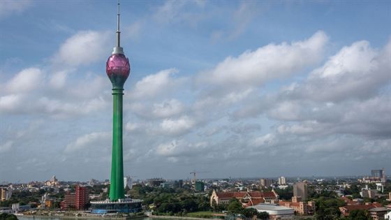 The Lotus Tower rising over the rooftops of Colombo under a bright cloudy sky.