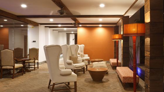 The library lounge at Colombo Court, wingback chairs and lamps under timber beams.