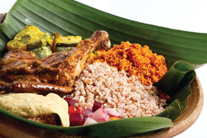 Rice and curry served on a banana leaf, chicken, sambol and pappadam alongside.