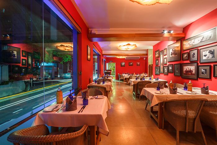 The Scarlet Room at Colombo Court, red walls hung with black and white photographs, tables set for dinner.