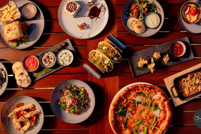 Sharing platters laid across a timber table at Cloud Café & Bar, pizza, dips, skewers and small plates.