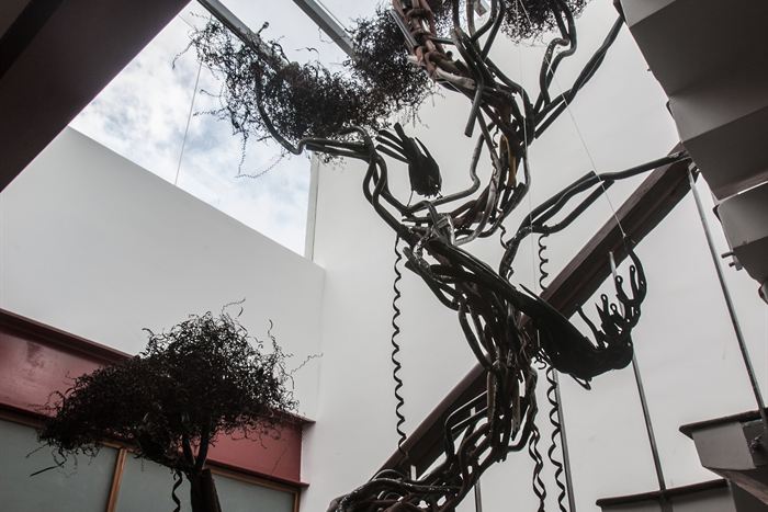 A sculpture of a tree welded from scrap steel, rising through the building towards a glass roof.
