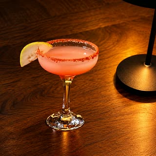 The Caribbean Crush, a coral-pink cocktail in a coupe glass with a salted rim and a slice of lime at Cloud Café & Bar.