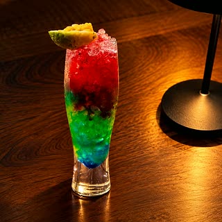 A layered cocktail in red, green and blue in a tall glass with a wedge of pineapple at Cloud Café & Bar.