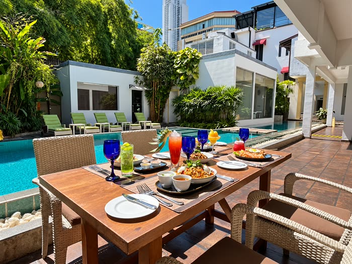 Lunch laid out on a table beside the pool at Amber Poolside, blue glassware and cold drinks under the trees.