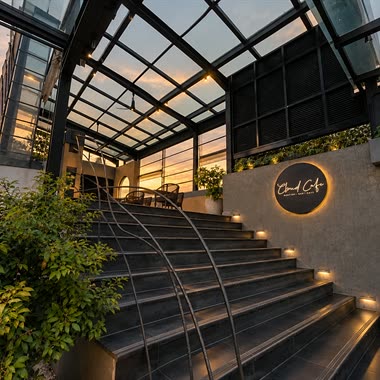 The stair up to Cloud Café & Bar under the glass roof, the sign at the top and the evening sky beyond.