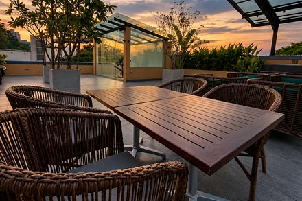 A long timber table on the rooftop at Cloud Café & Bar by day, the sky open above the glass roof.