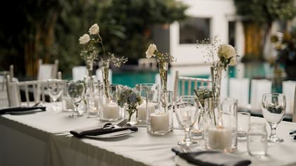A long table dressed in white beside the pool at Colombo Court, candles and glassware down its length.
