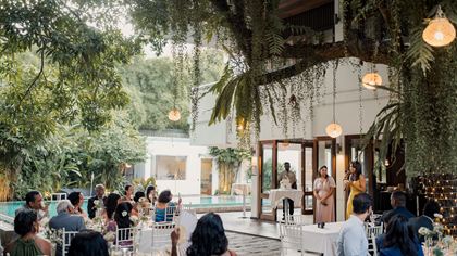 Guests seated for a reception in the garden at Colombo Court, pendant lights strung through the trees.