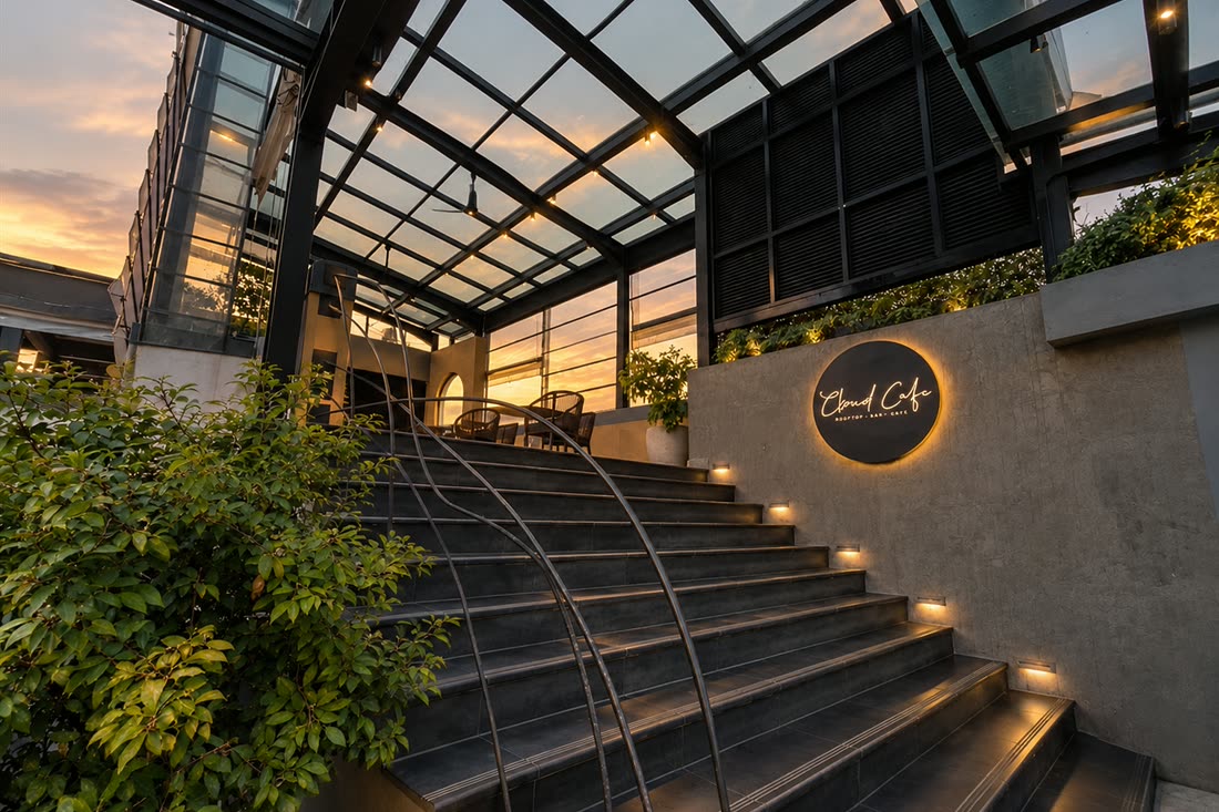 The stair up to Cloud Caf&eacute; & Bar under the glass roof, the sign at the top and the evening sky beyond.