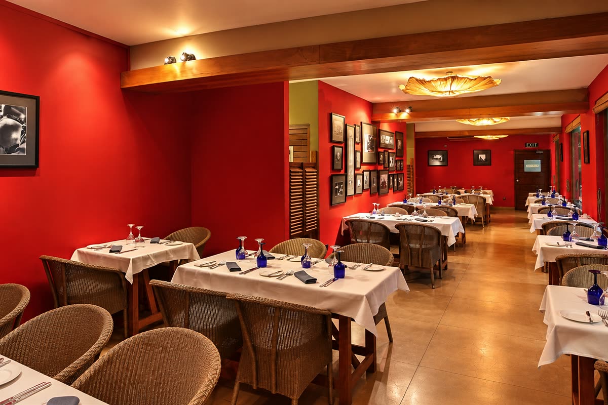The Scarlet Room at Colombo Court laid for private dining, timber tables with blue glassware along the deep red wall.