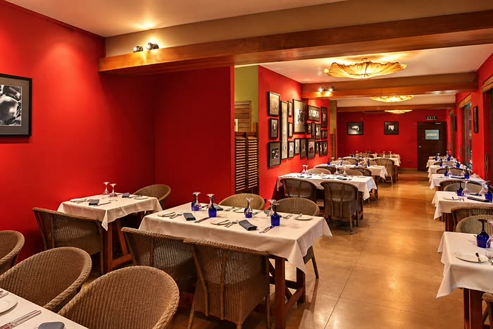 The Scarlet Room at Colombo Court laid for private dining, timber tables with blue glassware along the deep red wall.
