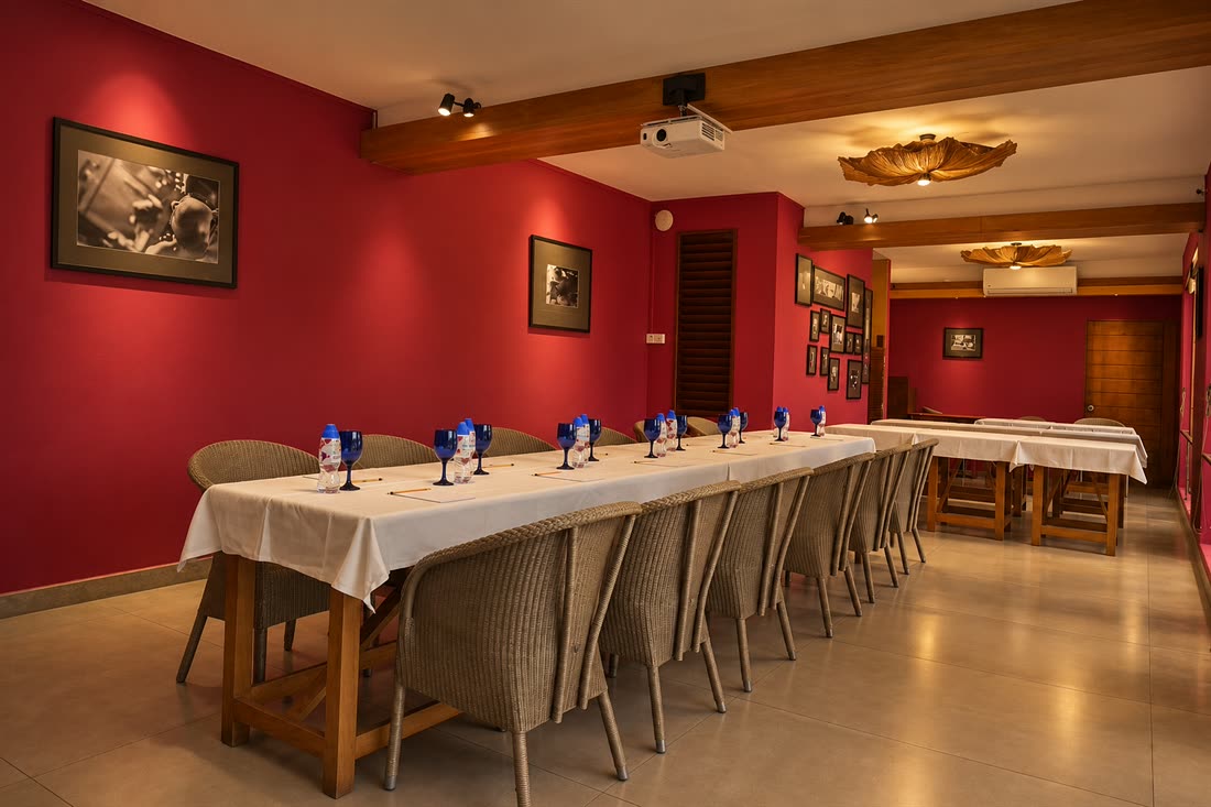 The Scarlet Room laid for private dining, a long table in white with blue glassware along the red wall.