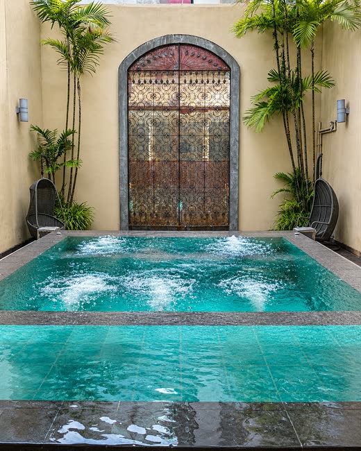 The jacuzzi at Colombo Court set before an antique arched door, palms on either side.
