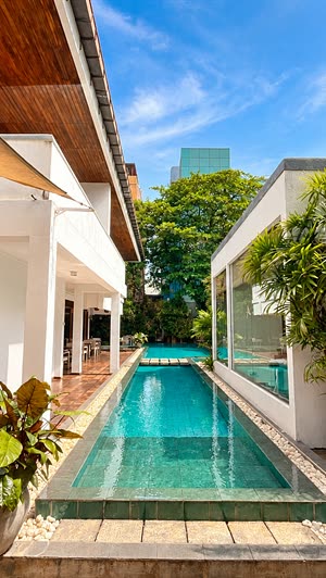 The pool at Colombo Court running the length of the garden between white walls and planting, laid for an evening by the water.