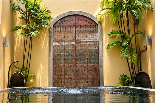 The jacuzzi at Colombo Court bubbling before an antique arched door, palms either side.