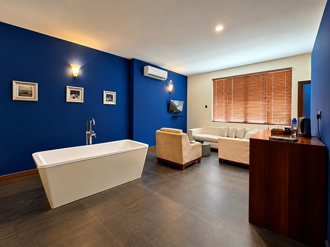 The Luxury Honeymoon Suite seen from the bath, armchairs and a sofa under the blue wall and the window beyond.