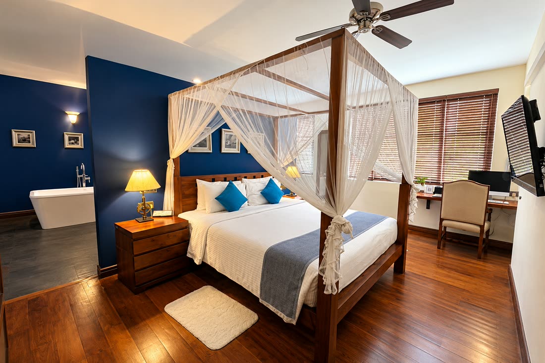 The Luxury Honeymoon Suite with the bath standing in the room beyond the bed, the window and desk to one side.