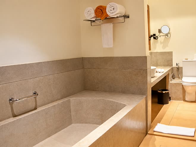 The bathroom in a Superior Deluxe room, a stone bath with rolled towels on the shelf above and the basin beyond.