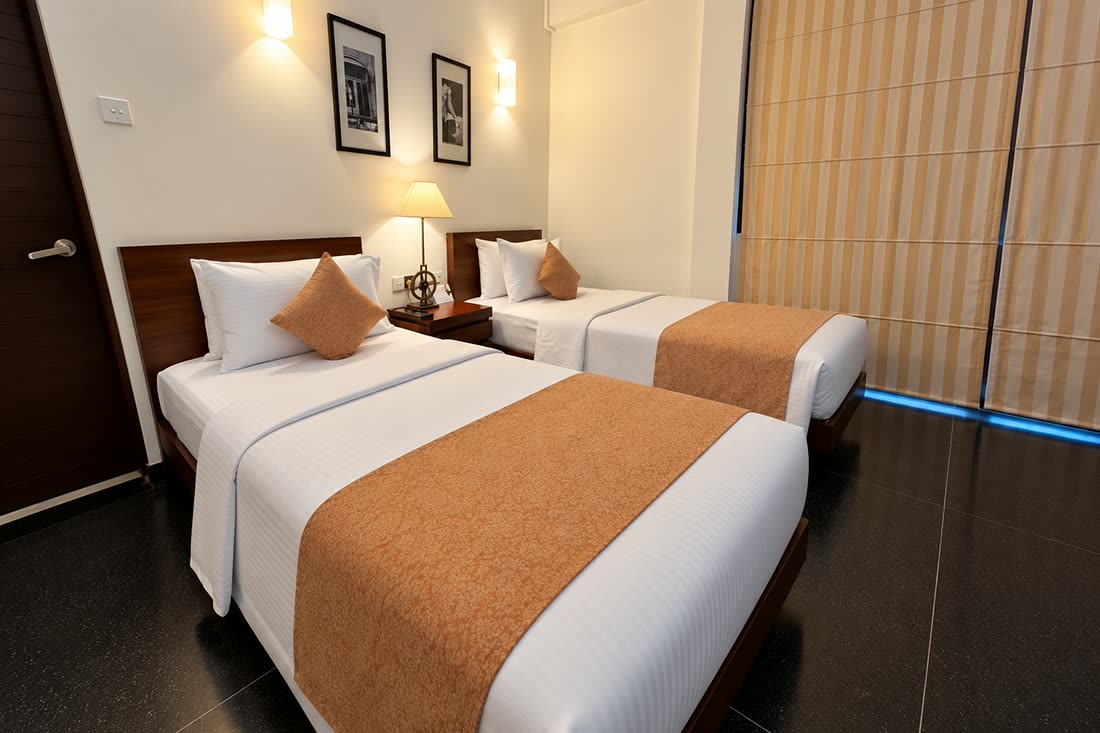 A Deluxe Twin room seen from the door, the two beds side by side beneath framed prints.