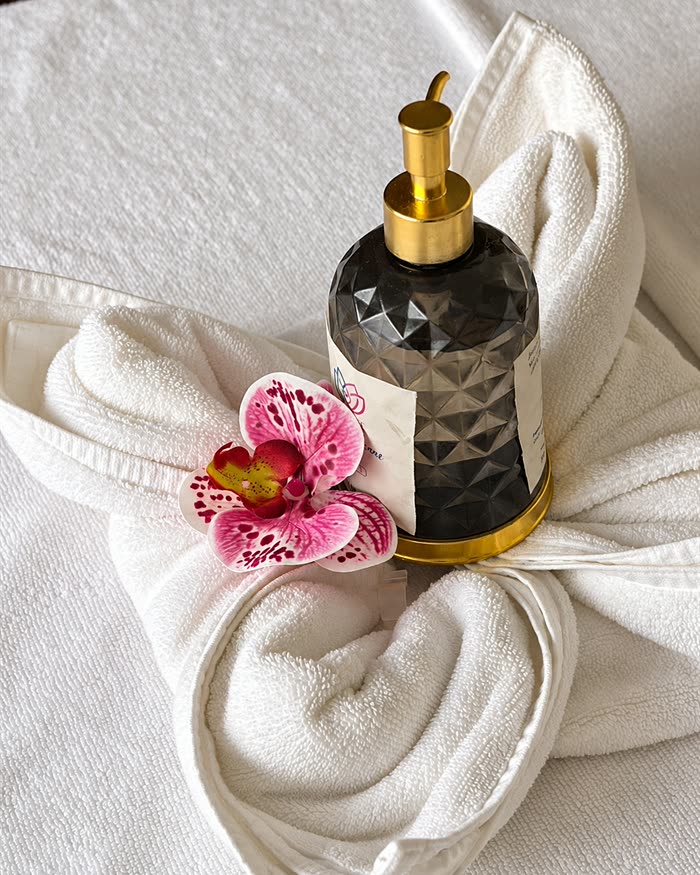 A bottle of massage oil set in a folded towel with a pink orchid at The Court Spa.
