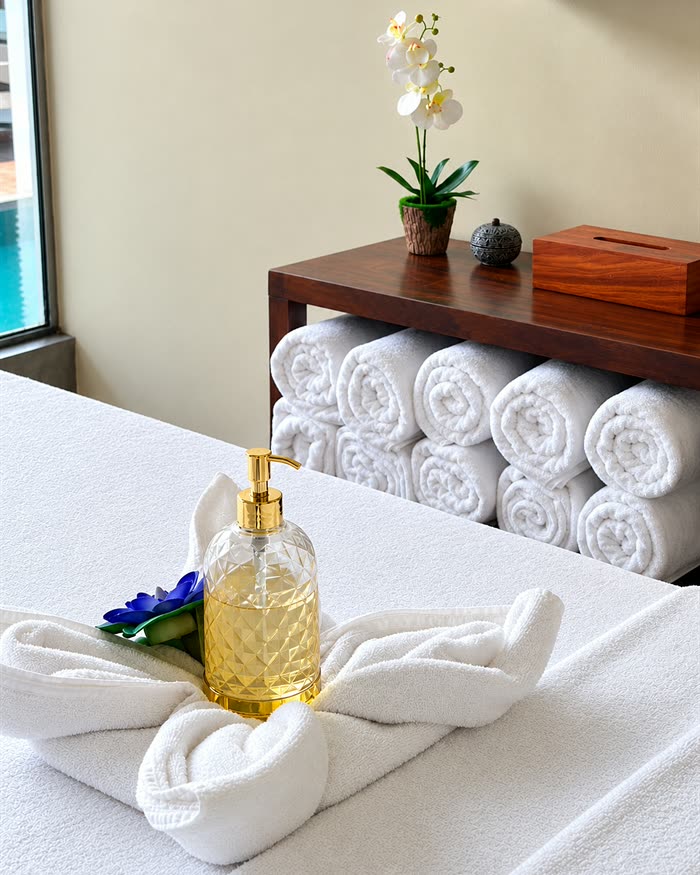 Rolled towels, an orchid and a bottle of oil on a treatment bed at The Court Spa.