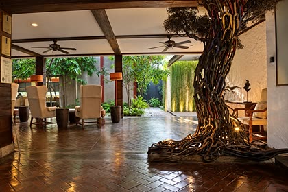 The atrium at Colombo Court, the tree sculpted from scrap steel rising past timber beams and winged armchairs.