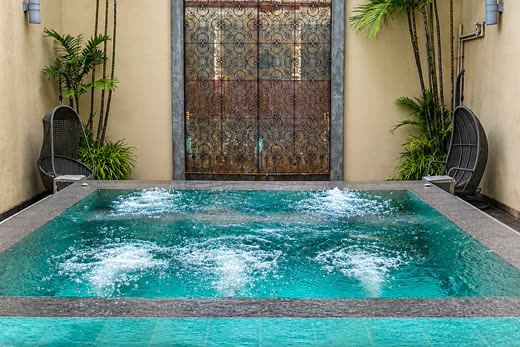 The jacuzzi at The Court Spa beneath an antique arched door, palms on both sides.
