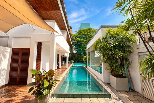 The pool at Colombo Court running the length of the garden between white walls and planting.