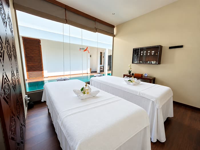The double treatment room at The Court Spa, two beds made up in white with the plunge pool through the glass.