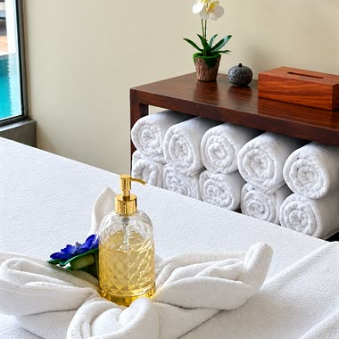 Rolled towels, an orchid and a bottle of oil on a treatment bed at The Court Spa.