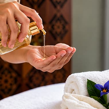 A therapist at The Court Spa pouring massage oil into the palm of one hand.