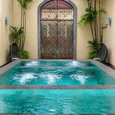 The jacuzzi at The Court Spa running beneath an antique arched door, palms on both sides.