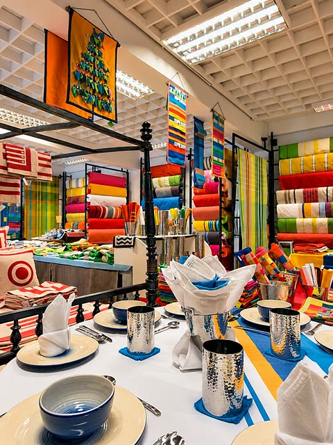 A handloom showroom in Colombo, bolts of bright striped fabric stacked behind a table laid with colourful linen.